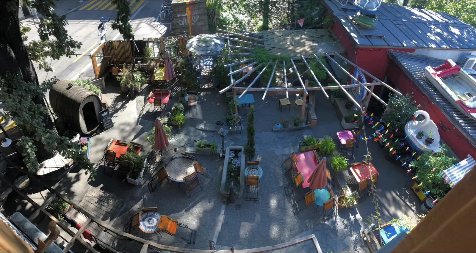 Bar am Damm aerial view — bird's-eye view of the colourful courtyard with seating areas, mature trees, and a central canopy structure