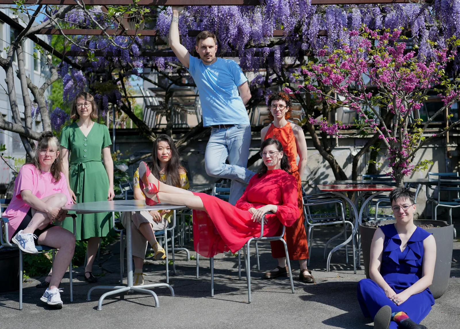 QSXZ team members posing playfully under blooming wisteria at an outdoor café